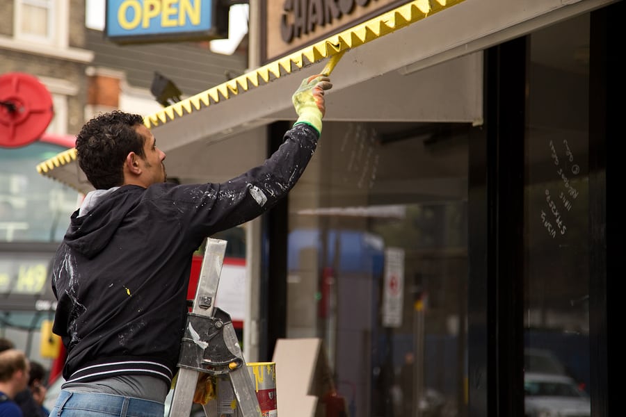 man painting yellow roof
